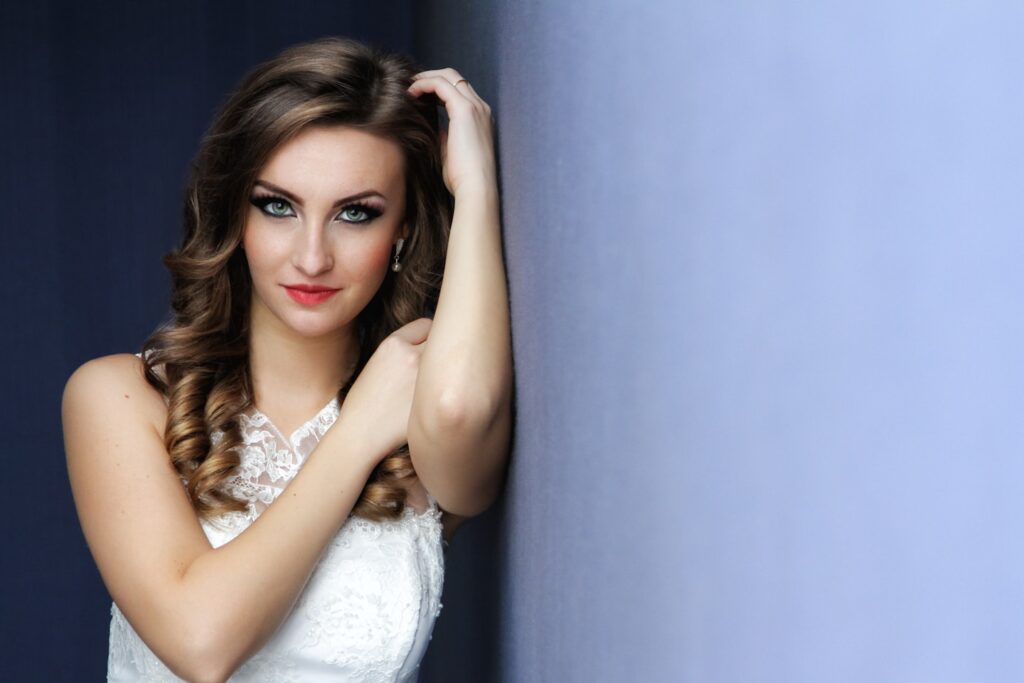 Bride leaning on a wall, posing and looking at the camera.